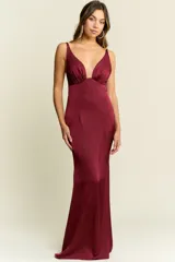 Vestido largo de satén color bordó, con escote profundo en V, tirantes finos y espalda descubierta. Presenta un corte ajustado en el torso que se ensancha suavemente hacia el ruedo.