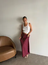 Pollera larga de fibrana color bordó con estampado de lunares blancos, tiro alto y corte amplio.