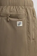 Pantalón jogger de corte regular confeccionado en tejido técnico ligero, con cintura elástica, bolsillos laterales con cierre y puños elásticos en los tobillos.