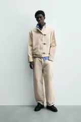 Jeans de hombre color beige claro, tiro medio, corte balloon fit con pierna relajada que se estrecha ligeramente hacia el bajo. Confeccionados en denim rígido de algodón, con cinco bolsillos y cierre frontal de cremallera y botón.