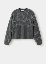 Jersey de punto gris con cuello redondo y adorno de plumas de avestruz en el pecho y las mangas, de corte recto y manga larga.