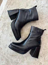 Botas negras de cuero sintético, con caña corta, plataforma y taco cuadrado. Cierre lateral con cremallera.