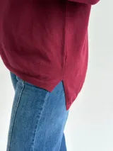 Sweater de punto en color bordó, con escote en V, mangas largas y diseño de corte recto con dobladillo ligeramente más largo en la parte posterior.