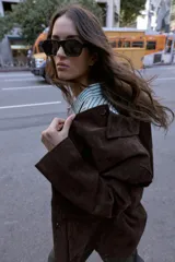 Cazadora de ante color marrón oscuro, con cuello solapa, manga larga y cierre frontal de botones. Incluye dos bolsillos delanteros de plastrón con solapa.