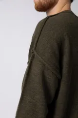 Sweater de punto grueso en color verde oliva, con diseño oversized, cuello redondo y mangas largas con puños acanalados.