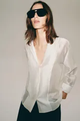 Camisa fluida Zara Woman Collection confeccionada en hilatura con mezcla de lyocell, en color amarillo claro. Presenta escote en pico, manga larga con puño ancho y cierre frontal oculto.