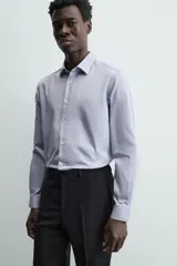 Camisa de algodón de manga larga, color celeste claro, con cuello italiano y cierre frontal de botonadura.