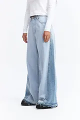 Jean de tiro alto con corte super oxford y silueta amplia. Presenta un diseño bicolor con paneles en diferentes tonos de azul y ruedo desflecado.