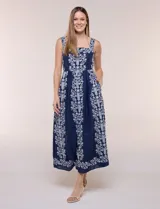 Vestido midi azul marino con bordados florales blancos, escote cuadrado, breteles anchos y falda amplia con bolsillos.