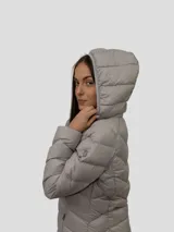 Campera puffer color beige con capucha, cierre frontal con cremallera y bolsillos laterales. Relleno de plumón (90% plumón, 10% plumas).