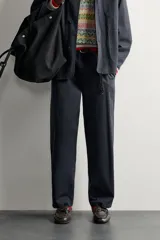 Pantalón chino regular fit confeccionado en algodón, color negro, con bolsillos frontales, bolsillos traseros de vivo con botón y cierre frontal con cremallera y botón. Colección especial Aaron Levine x ZARA.