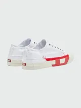Zapatillas bajas de lona blancas con detalles deshilachados y aplique lateral de goma roja con el logo 'D' de Diesel. Presentan puntera de goma color crema y cordones blancos.