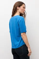 Remera blanca de manga corta raglán con detalle de vainillas, cuello redondo y corte clásico.