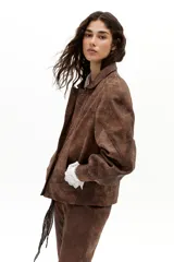 Chaqueta oversized de cuero de oveja color marrón antiguo, con hombros exagerados, cuello camisero redondeado, bolsillos frontales y botones a presión forrados. Cuenta con forro capitoneado y bolsillo interno.