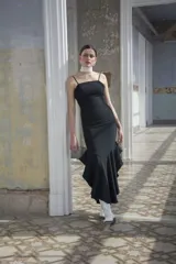 Vestido midi negro de corte sirena al cuerpo, con escote recto, tirantes finos y falda con volados en el bajo.