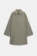 Trench oversize de Zara Woman Collection, confeccionado en hilatura de algodón. Presenta cuello solapa, manga larga, bolsillos delanteros y cierre frontal con botones ocultos bajo solapa.
