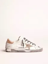 Zapatillas Golden Goose modelo Super-Star, de cuero blanco con efecto desgastado. Estrella de gamuza color beige en el lateral exterior y contrafuerte de cuero metalizado color dorado. Cordones con estampado animal print.