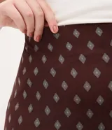 Falda midi de tul con estampado de corbatas, cintura elástica y diseño con volados. Presenta un forro más corto que crea un efecto de transparencia en el ruedo.