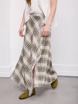 Falda larga de corte cruzado con estampa a cuadros en tonos beige, verde militar y azul oscuro, con detalle de flecos en el borde delantero.