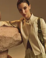 Campera estilo motero de símil cuero en color beige, con cuello alto, cierre frontal asimétrico y paneles acolchados en los hombros.