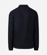 Polo de manga larga color beige claro, confeccionado en tejido texturizado (posiblemente acanalado o waffle). Presenta un cuello polo con escote profundo en V sin botones.