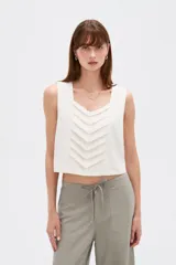 Musculosa sin mangas de color natural con cuello cuadrado y detalles de pliegues frontales en forma de chevrón.