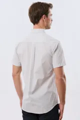 Camisa de manga corta con microcuadros en tonos celestes y blancos, calce slim, cuello con botones y bolsillo frontal con logo bordado.