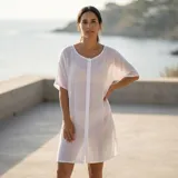 Camisa holgada blanca de manga corta y largo medio, confeccionada en mezcla de algodón, con cierre frontal de botones.