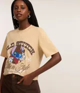 Remera de algodón color beige, modelo t-shirt, con cuello redondo, manga corta y estampa frontal de Stitch con temática de cowboy y lettering "Wild Stitch".