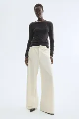 Pantalón amplio color crudo confeccionado en punto bouclé, con elástico oculto en la cintura, cierre decorativo con botón, bolsillos delanteros y bolsillos de parche en la parte trasera.