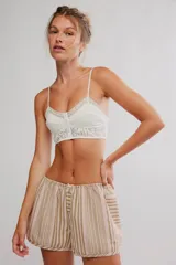 Bralette largo de color blanco, confeccionado en tela plumetí con escote en V y detalles de encaje. Cuenta con tirantes finos regulables, cierre frontal de botones y banda inferior de encaje.