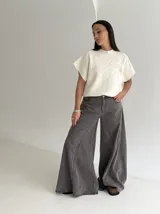 Chaleco tejido de punto color crudo, con cuello redondo y diseño de flor en relieve en el frente. Presenta un corte holgado y mangas cortas con terminación acanalada.