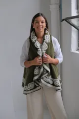 Chaleco abierto de tejido de punto color verde oliva, con bordes decorados con un diseño floral en relieve de color blanco. Presenta una caída fluida y un estilo envolvente.