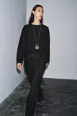 Blusa de cuello redondo y manga larga, confeccionada en tejido fluido con acabado satinado. Presenta un diseño de corte holgado, bajo recto y cierre en la espalda mediante una pequeña abertura con botón.