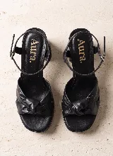 Sandalia de taco alto ancho con plataforma delantera y diseño elegante y sofisticado. Presenta una capellada con tiras anchas y detalle de nudo central. Incorpora pulsera ajustable con hebilla en el tobillo.