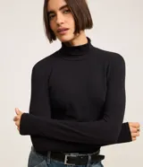 Suéter de cuello alto y manga larga, confeccionado en algodón con elastano. Presenta un diseño básico y ajustado al cuerpo.