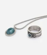 Kit compuesto por collar de cadena con dije ovalado y anillo ancho con detalles grabados, ambos de metal plateado envejecido con piedra azul turquesa.