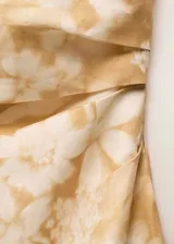Vestido midi de lino con estampado floral en tonos amarillos y blancos. Presenta un diseño asimétrico con un solo hombro, cintura drapeada y una abertura lateral en el bajo.