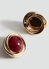 Aros circulares con diseño entrelazado dorado y una piedra central de resina color burdeos.