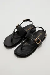 Sandalias negras de eco cuero estilo chunky, con diseño de tiras cruzadas y hebilla metálica dorada en la parte superior. Cuenta con tira ajustable en el talón.