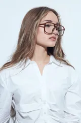 Camisa blanca de manga larga con cuello clásico y cierre frontal de botones. Presenta un diseño entallado con frunces decorativos en la parte central delantera.