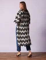 Cardigan largo de crochet color crudo con diseño de ondas en negro.