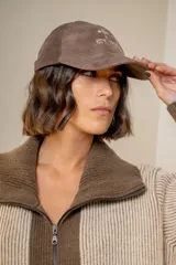Gorra de cuero color chocolate con bordado frontal en hilo color crema que incluye un símbolo de flor de lis y la inscripción 'EST. 1994'.