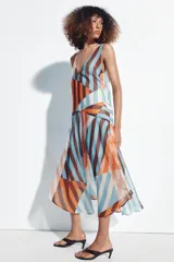 Vestido midi de tirantes con diseño geométrico y de rayas verticales en tonos salmón, celeste, marrón y blanco. Cuenta con escote en V y tirantes cruzados en la espalda.