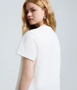 Remera de algodón color blanco con cuello redondo y mangas cortas. Presenta una estampa frontal en color azul con la frase 'Born to Shine' y una ilustración de un perro trabajando en una computadora.
