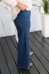 Jean de tiro medio en color azul oscuro, con costura vertical decorativa en el centro de cada pierna y cierre frontal con botón metálico.