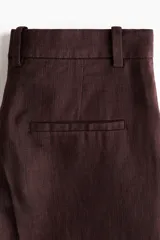 Pantalón sastrero de tiro alto en sarga de mezcla de lino y lyocell, color bordó, con piernas rectas, pliegues delanteros y traseros, bolsillos al bies y presillas para cinto.