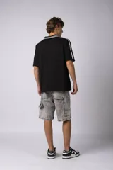 Remera tipo chomba de tejido de punto color blanco, con cuello polo y diseño de rayas verticales sutiles. Presenta estampado gráfico frontal con texto y logo, además de detalles de rayas negras en los hombros.