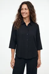 Camisa color negro, con cuello camisero, cierre frontal con botones y mangas tres cuartos.