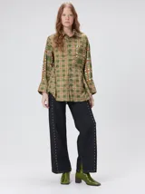 Camisa de seda con cuello camisero, manga larga y bolsillo frontal. Presenta un diseño estampado geométrico de cuadrados en tonos marrones y azul oscuro.